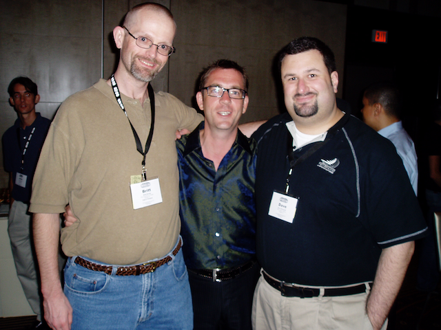 britt-ted-allen-david Britt, Ted Allen, and David stand together with their arms around one another, smiling at the camera. Britt and David wear conference badges.